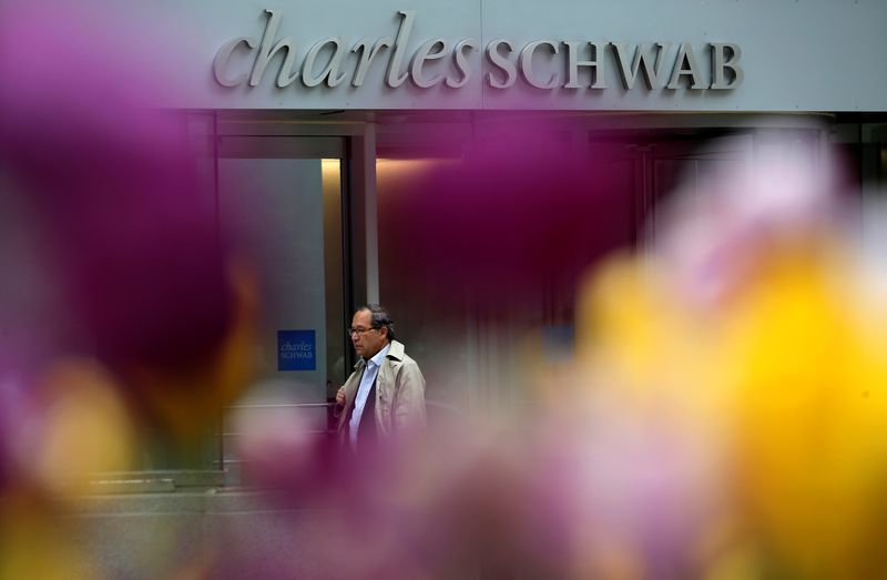 A man walks past a Charles Schwab investment branch in