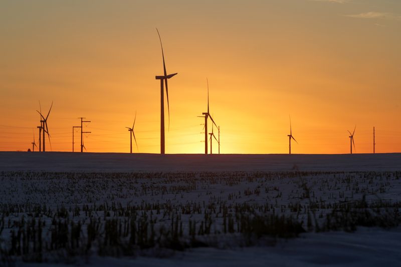A wind farm shares space with corn fields the day