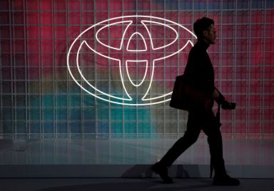 A man walks past a Toyota logo at the Tokyo