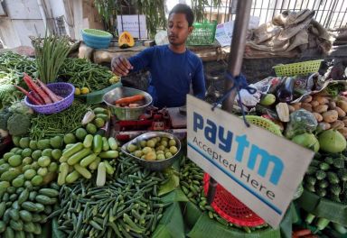 FILE PHOTO: A vendor weighs vegetable next to an advertisement