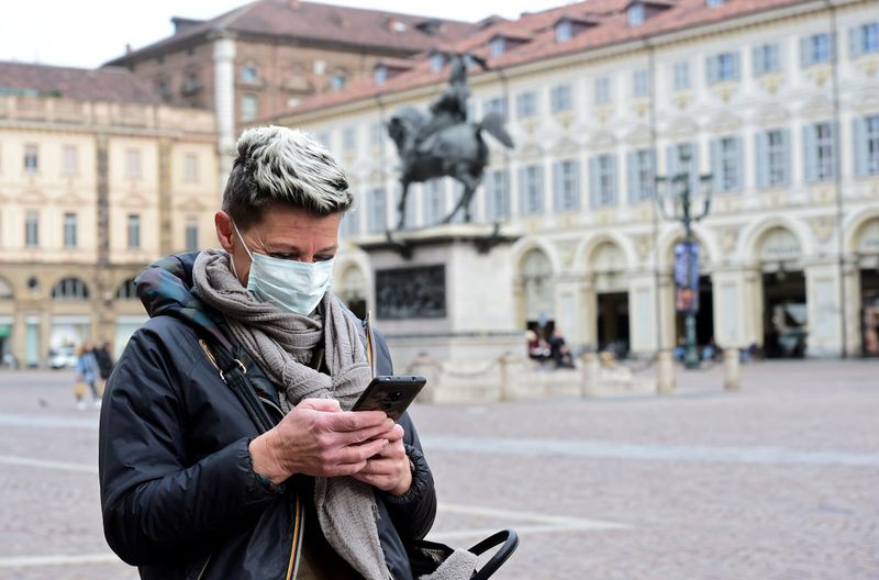 FILE PHOTO: Woman wearing a protective mask uses her mobile