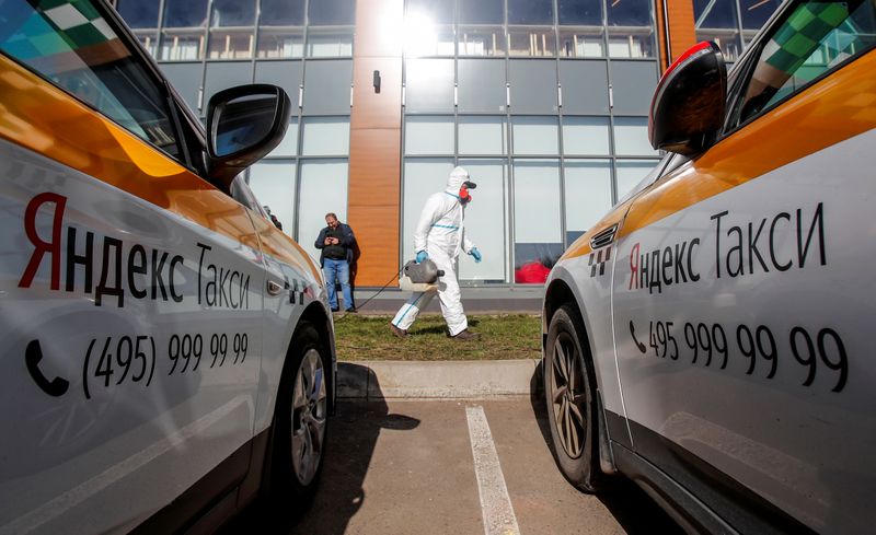FILE PHOTO: A specialist wearing protective gear sanitizes cars at