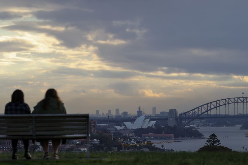 People sit on a bench overlooking the Sydney Opera House