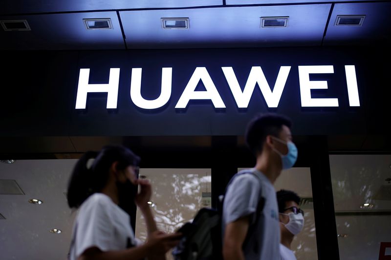 People walk past a Huawei store at a shopping mall