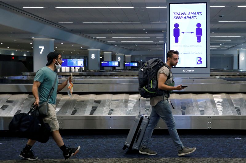 FILE PHOTO: Travelers pass a sign alerting them to distance