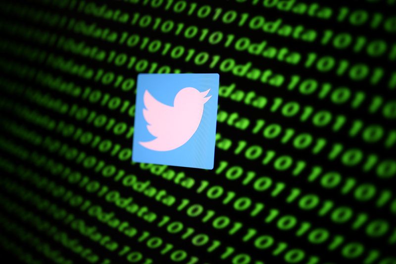 The Twitter logo and binary cyber codes are seen in