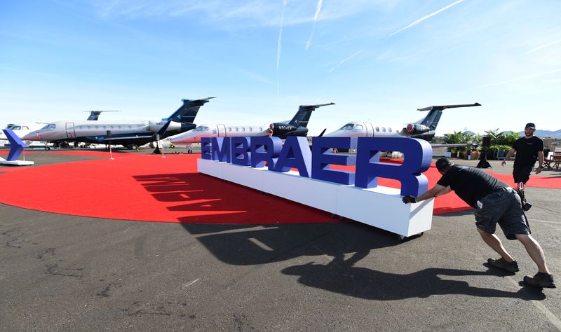 Workers set up at the Embraer booth prior to the