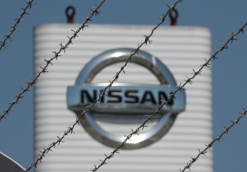The logo of Nissan is seen through a fence at
