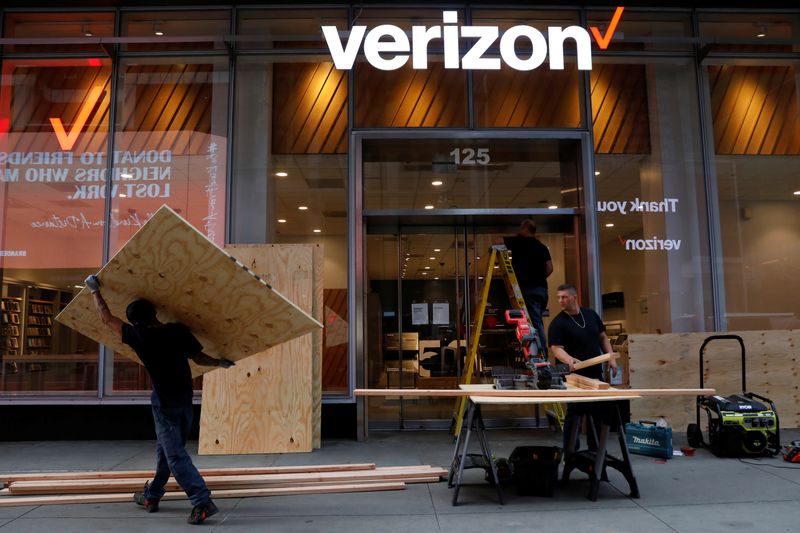 Workers board up a Verizon store in midtown Manhattan during