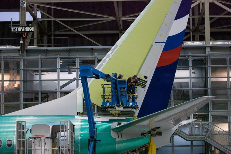 Boeing employees work on the tail of a Boeing 737
