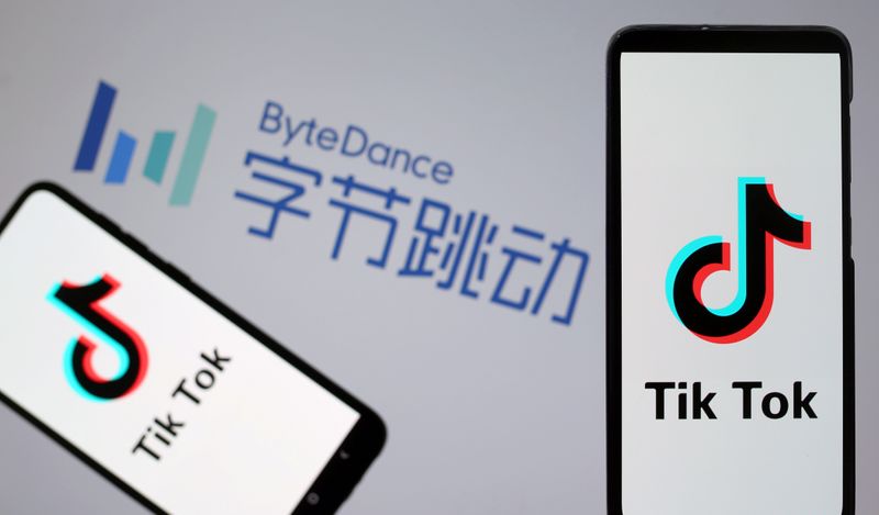 Tik Tok logos are seen on smartphones in front of