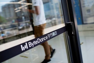 FILE PHOTO: Man walks by a logo of ByteDance, which