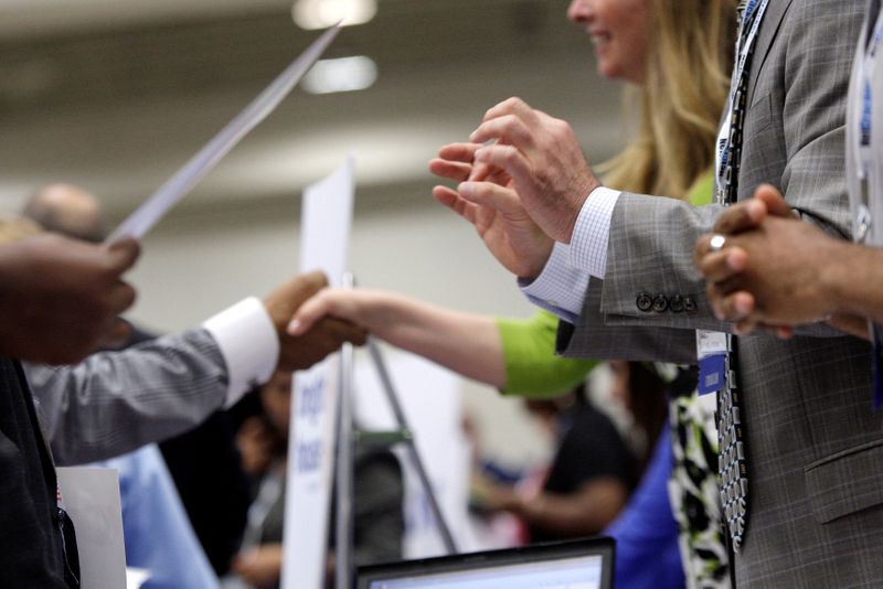 Corporate recruiters gesture and shake hands as they talk with