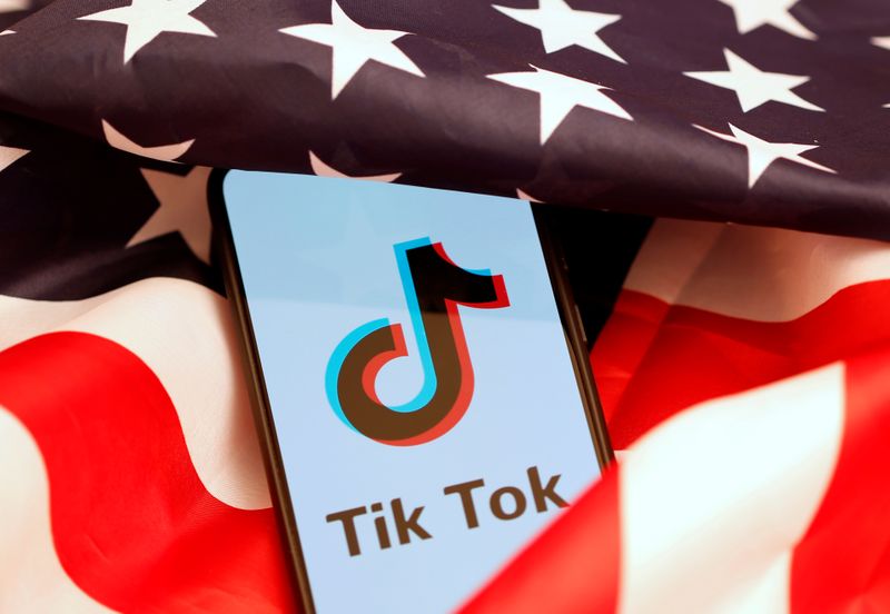 Tik Tok logo is displayed on the smartphone while standing