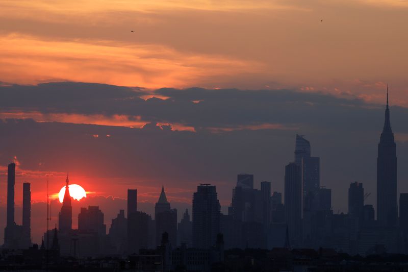 Sunset is seen behind the skyline of Manhattan on the