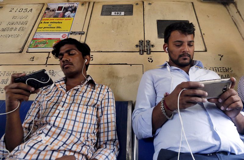 FILE PHOTO: Commuters watch videos on their mobile phones as