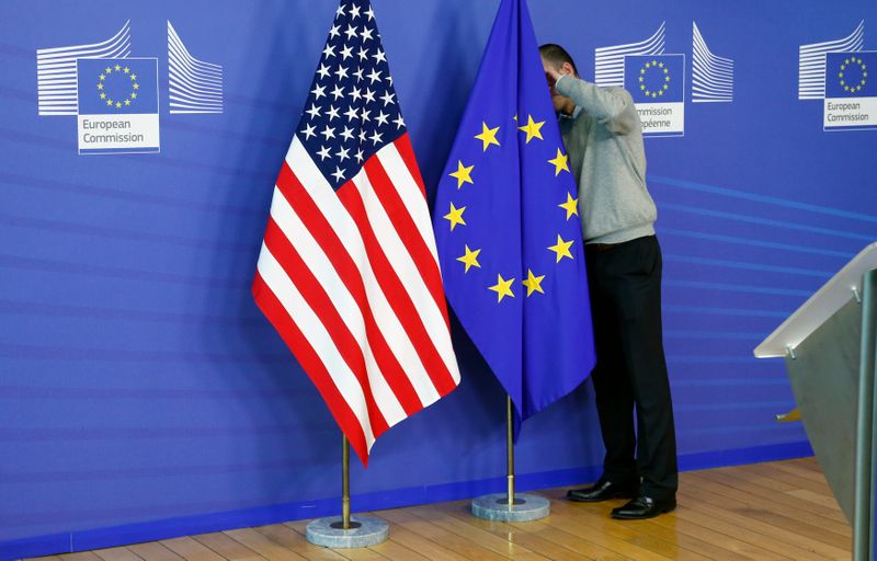 A worker adjusts EU and U.S. flags at the start