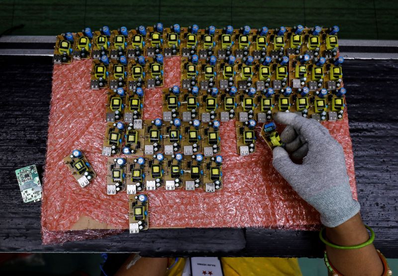 FILE PHOTO: A worker arranges battery charger circuit boards at