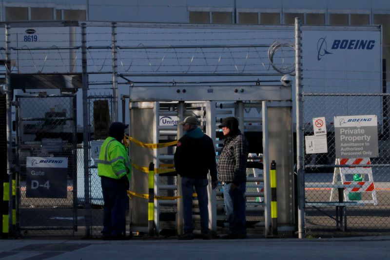 Employees and contractors stand at a gate to the Boeing