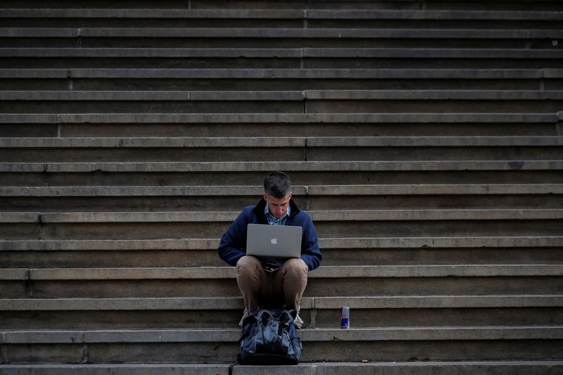 A man uses his Apple laptop on the steps of