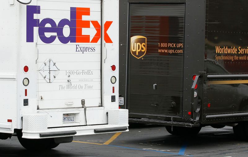 A FedEx truck is parked next to a UPS truck