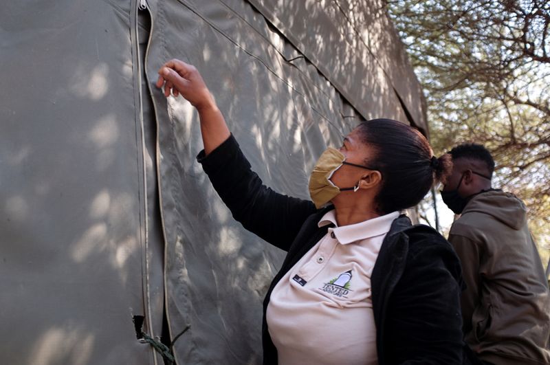 Workers check tents  at a safari camp during the