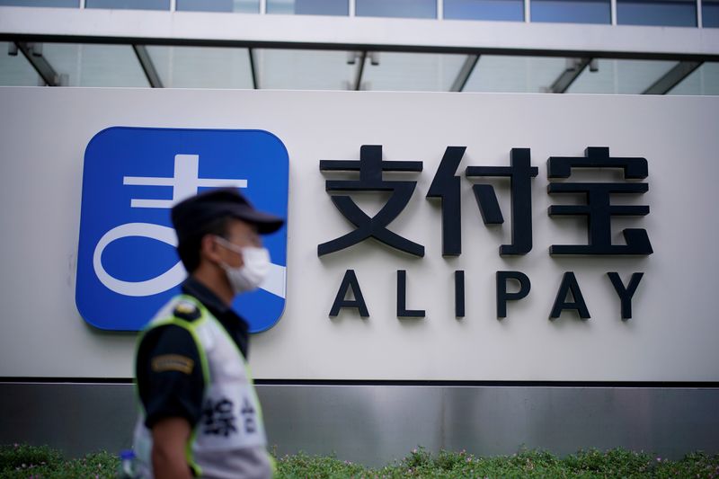 FILE PHOTO: A security guard walks past an Alipay logo
