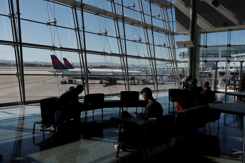 Travelers sit in a lounge area as Delta Air Lines