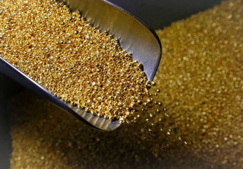 An employee takes granules of 99.99 percent pure gold at