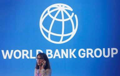 A participant stands near a logo of World Bank at
