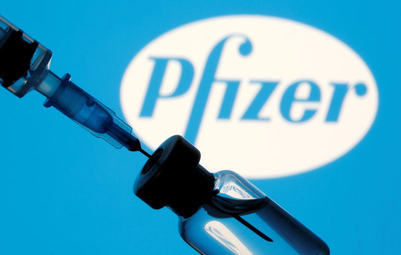 Vial and sryinge are seen in front of displayed Pfizer