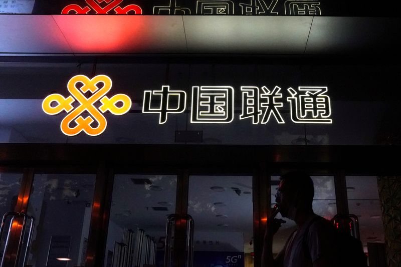 FILE PHOTO: Man smokes in front of a China Unicom