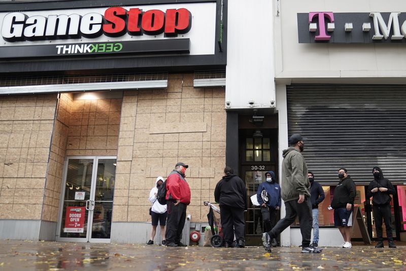Outside a GameStop store people line up to purchase a
