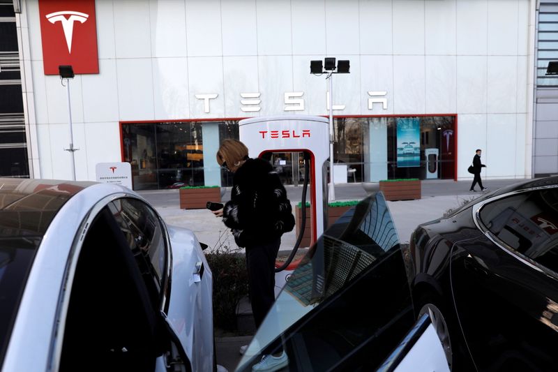 FILE PHOTO: Woman charges a Tesla car in front of