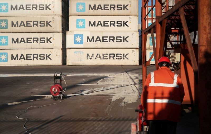Worker is seen next to Maersk shipping containers at a