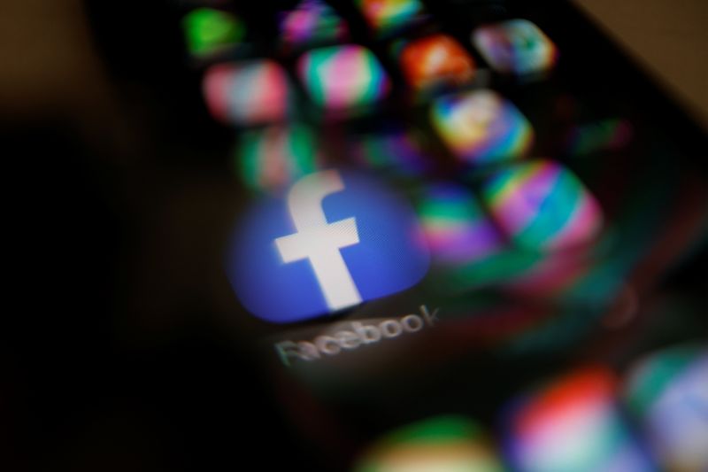 Facebook logo displayed on a mobile phone is seen through