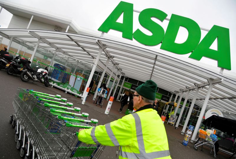 FILE PHOTO: A worker pushes shopping trolleys at an Asda