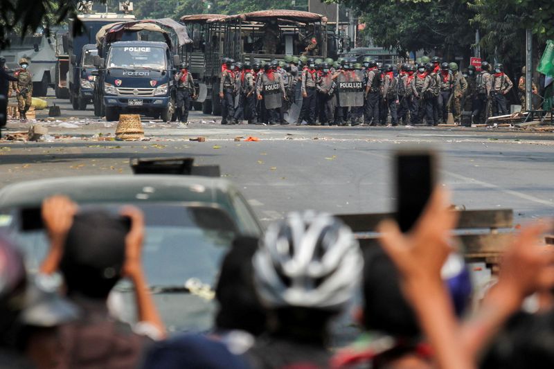 Police stand on a road during an anti-coup protest in