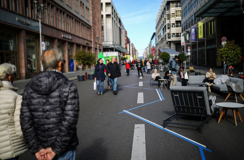People walk along Friedrichstrasse street which is closed for traffic
