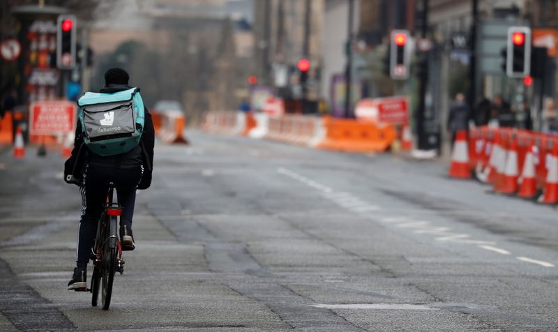 A deliveroo delivery driver cycles through the centre of Manchester
