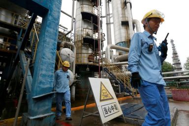 FILE PHOTO: Technicians walk down the refinery which produces ethanol