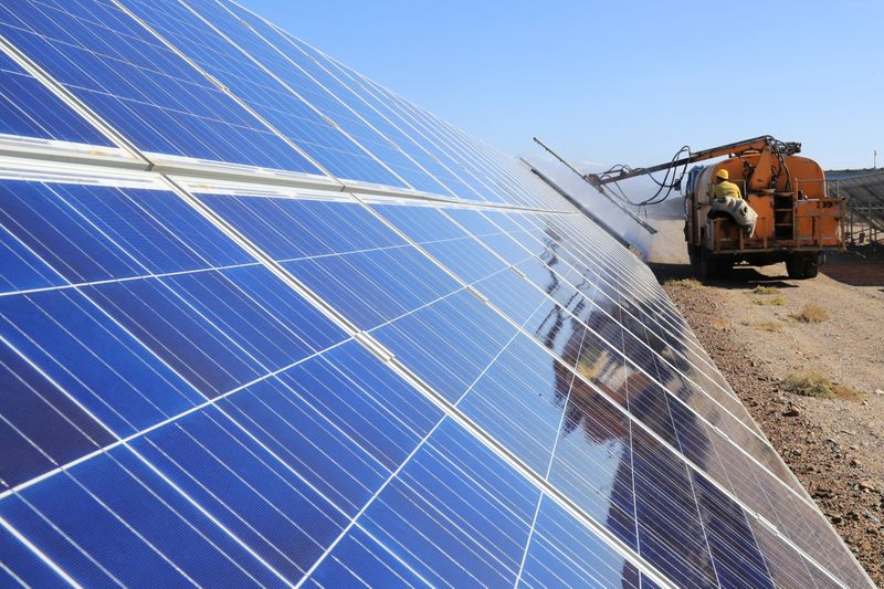 Worker operates a machinery to clean solar panels at a