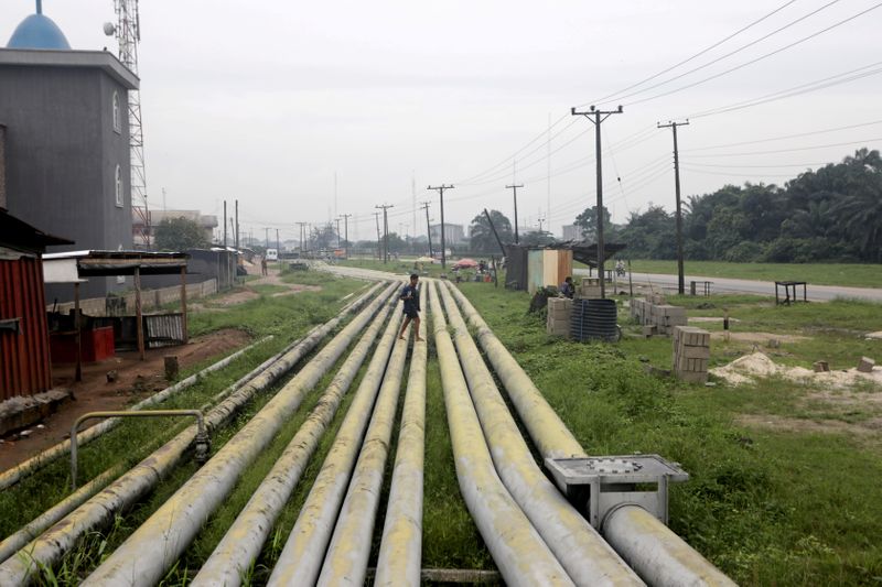 FILE PHOTO: A woman walks over pipelines crisscrossing Ogoniland in