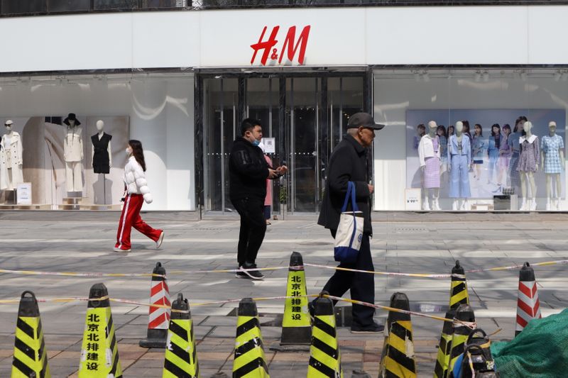 People walk past an H&M store at a shopping complex