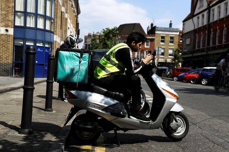 FILE PHOTO: A Deliveroo scooter driver takes a break between