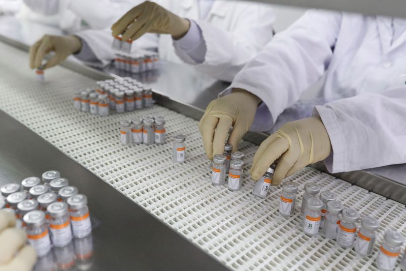 FILE PHOTO: Workers place Sinovac COVID-19 vaccine vials in trays