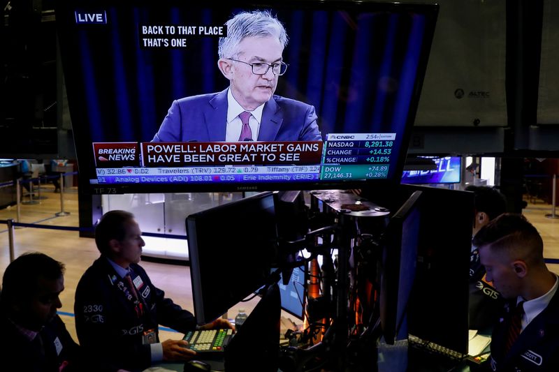 FILE PHOTO: Traders work as a screen shows Federal Reserve