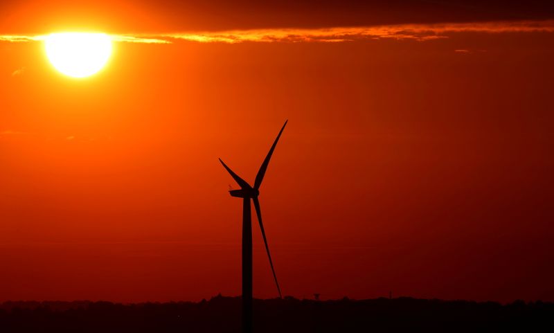 FILE PHOTO: The sun rises behind a wind turbine in