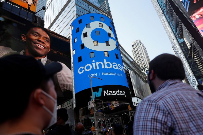 FILE PHOTO: People watch as the logo for Coinbase Global