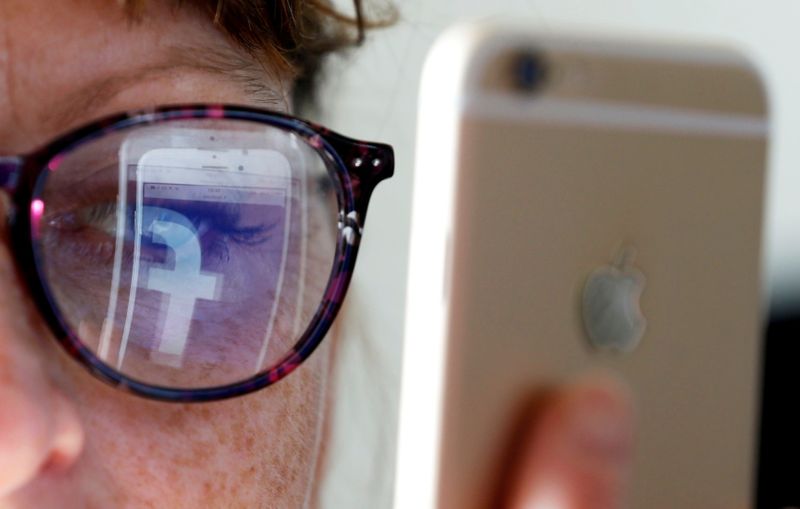 FILE PHOTO: The Facebook logo is reflected on a woman’s